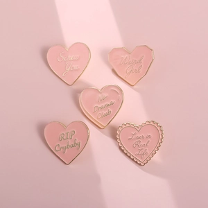 Détail d'un lot de 5 broches émaillées roses en forme de cœur avec texte géométrique