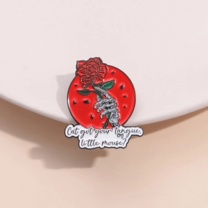 Gothic skull hands holding a red rose enamel pin with text on a white pedestal
