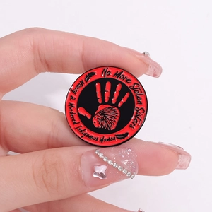 Red handprint indigenous enamel pin with No More Stolen Sisters text on white background