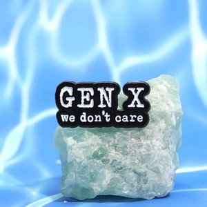 Minimalist Gen X black enamel brooch with white text on a natural stone base