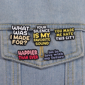Set of five enamel music lyric pins on denim jacket featuring trendy letter badge designs