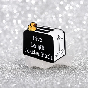Gros plan d'un pin's en émail grille-pain avec canard et texte Live Laugh Toaster Bath