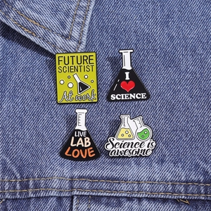 Set di quattro spille smaltate a tema scientifico esposte su tessuto denim blu