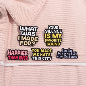 Close-up of five colorful lyric enamel pins on a pink denim jacket collar detail