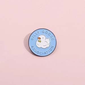 Blue enamel pin with a white goose and Silly Goose Association text in round frame