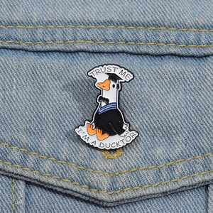 Close-up of duck doctor enamel pin with Trust Me I'm a Ducktor text on denim fabric