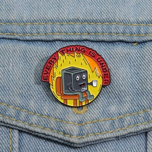 Detail view of Ctrl key character enamel pin with fire design on denim fabric jacket