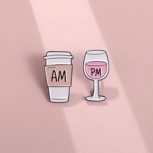 Creative AM PM enamel pins featuring a coffee cup and wine glass on a pink background