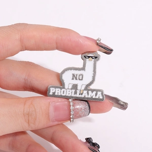 Detailed view of an enamel llama pin with 'NO PROBLLAMA' text being held to show scale