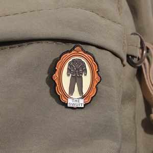 Macro detail of the orange vintage frame enamel brooch featuring the brown suit design