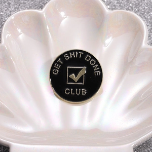 Round black enamel badge with gold trim and Get Shit Done Club text for clothing
