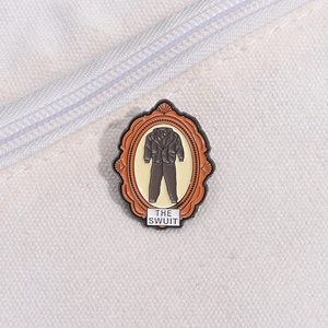 Artistic suit enamel pin with orange frame and THE SUIT text on a canvas bag