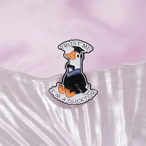 Cartoon Emaille Brosche weiße Ente im Talar mit Aufschrift Trust Me I'm a Ducktor Text