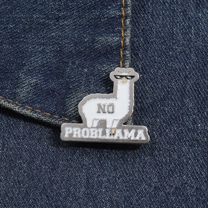 Detail of alpaca enamel pin with No Probllama text on dark blue denim fabric