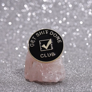Round black and gold enamel badge with GET SHIT DONE slogan on a crystal stone