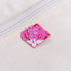 Cartoon pink monster enamel pin badge with vibrant blue eyes on white canvas fabric