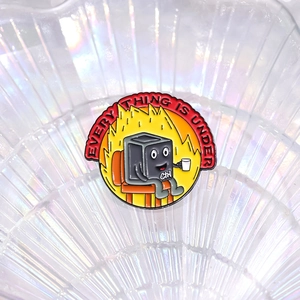 Detailed macro shot of an enamel pin featuring a black Ctrl key character in orange fire