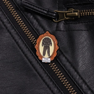 Macro shot of an orange enamel suit brooch pinned on a black leather jacket with zippers