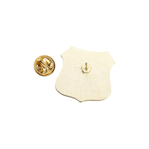 Detail view of golden metal shield pin back and butterfly clutch fastener components