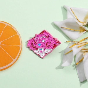 Cartoon pink monster enamel pin badge shown from a 45-degree angle on a green background