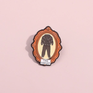 Detail view of retro frame enamel pin with THE SWUIT suit design on pink background