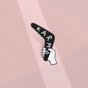 Detailed view of enamel karma boomerang pin featuring a hand-drawn white graphic hand