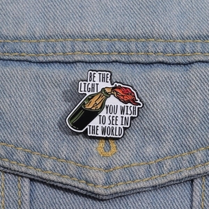 Detail view of flame bottle enamel pin on denim jacket with inspirational quote