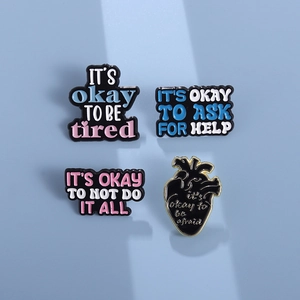 Nahaufnahme von vier Emaille-Pins mit Text und schwarzem Herz auf blauem Hintergrund