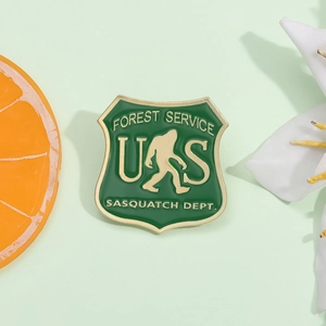 Macro shot of green enamel Big Foot shield badge with gold trim and forest imagery