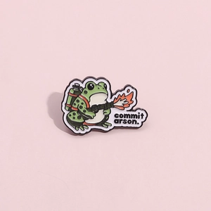 Épingle émaillée grenouille rigolote avec texte commit arson sur fond rose pastel