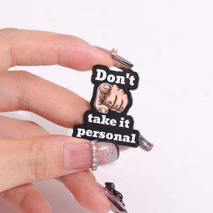 Detail of creative enamel pin showing finger gesture with Don't Take It Personal text