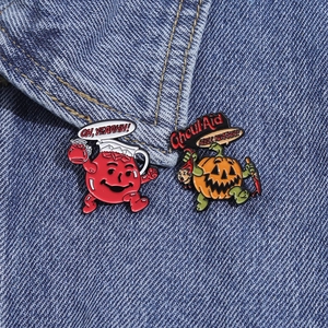 Detailed view of Halloween pumpkin and red pitcher enamel pins on denim fabric texture