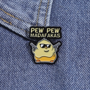 Détail du pin's en émail poussin cartoon avec texte Pew Pew Madafakas sur tissu denim