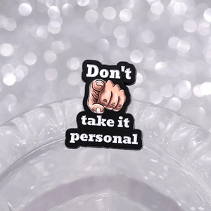 Gros plan du pin's avec texte 'Don't take it personal' sur le bord d'un verre