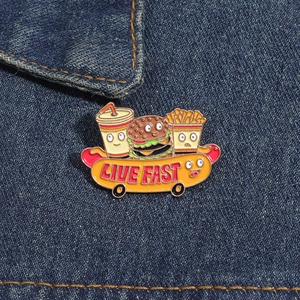 Detail of creative enamel pin showing fast food characters on a hot dog skateboard