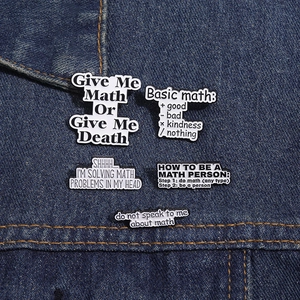 Detailed close-up of five black and white enamel math pun badges on denim fabric