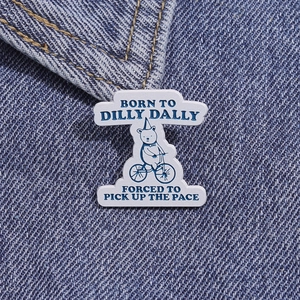 Detailed close-up of a cartoon bear cycling enamel pin on a denim jacket collar
