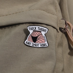 Détail d'un badge en émail avec texte humoristique sur un sac à dos en toile verte