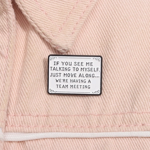 Detail of enamel brooch on pink denim with text IF YOU SEE ME TALKING TO MYSELF...