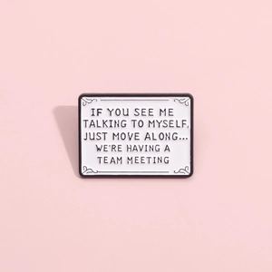Detailed close-up of white enamel brooch with scroll trim and witty quote text