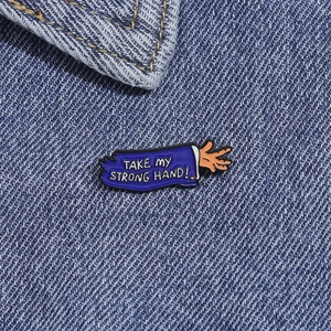 Detalle del pin esmaltado con texto sobre fondo de tela vaquera azul en primer plano