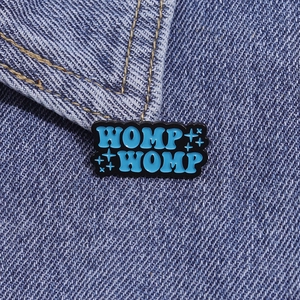 Spilla smaltata blu WOMP WOMP con design a stelle su sfondo di giacca di denim