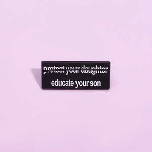 Nahaufnahme der schwarzen geometrischen Brosche mit weißem educate your son Slogan-Text
