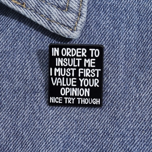 Macro view of rectangular black enamel pin with white text on blue denim fabric