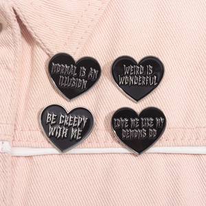 Macro detail of four heart-shaped black enamel pins on a pink denim jacket