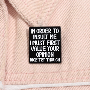 Detail of black enamel pin with sarcasm text on pink denim fabric background
