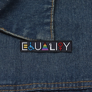 Detail of EQUALITY enamel pin with rainbow stripes and social symbols on denim jacket