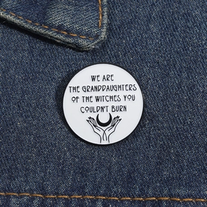 Detailed macro view of enamel brooch on denim showing inspirational text and moon graphic