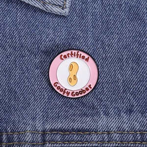 Vista macro della spilla smaltata Certified Goofy Goober su sfondo di denim blu scuro
