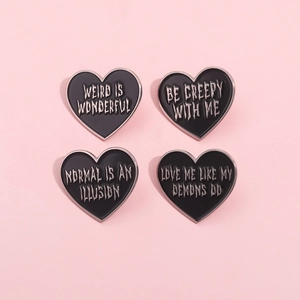 Set of four black enamel heart-shaped brooches with silver gothic text on pink background